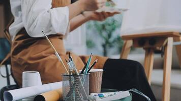 over- de schouder selectief focus schot van mannetje artiest gebruik makend van borstel terwijl toevoegen kleur verf naar potlood tekening Aan canvas video