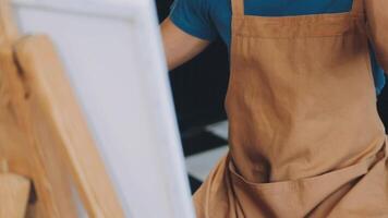 over- de schouder selectief focus schot van mannetje artiest gebruik makend van borstel terwijl toevoegen kleur verf naar potlood tekening Aan canvas video