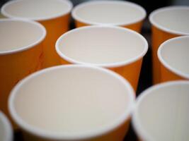 Empty orange paper cups stand in a row. Preparing for a party. Environmentally friendly product. No plastic. Close-up shot. photo