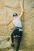 Young athletic woman in equipment doing rock climbing outdoors. Training area for outdoor activities. Extreme sport. photo