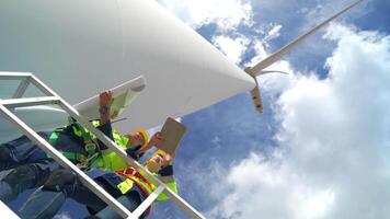 ingenieros trabajando en trabajo de campo al aire libre. trabajadores cheque y inspeccionar construcción y máquina alrededor el edificio proyecto sitio. viento turbinas para eléctrico limpiar energía y ambiente sostenibilidad. video