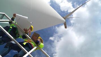 ingenjörer arbetssätt i fältarbete utomhus. arbetare kolla upp och inspektera konstruktion och maskin runt om de byggnad projekt webbplats. vind turbiner för elektrisk rena energi och miljö hållbarhet. video
