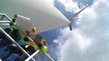 ingegneri Lavorando nel lavoro sul campo all'aperto. lavoratori dai un'occhiata e ispezionare costruzione e macchina in giro il edificio progetto luogo. vento turbine per elettrico pulito energia e ambiente sostenibilità. video