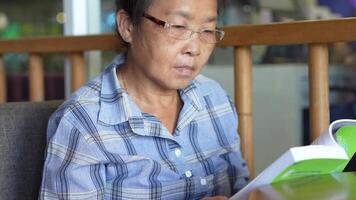 asiatisk senior gammal kvinna är läsning bok. video