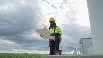 africano ingegnere Lavorando nel lavoro sul campo. lavoratore seduta e ispezionare costruzione e macchina in giro il progetto luogo. vento turbina elettrico di pulito risorsa energia e ambiente sostenibile. video