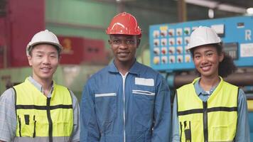 Gruppe Arbeiter Fabrik afrikanisch und asiatisch Männer und Frauen Stehen mit Vertrauen und Erfolg. Menschen Arbeiten im Arbeitsplatz von industriell schwer Maschine Fabrik. jung Erwachsene im Werdegang von Industrie. video