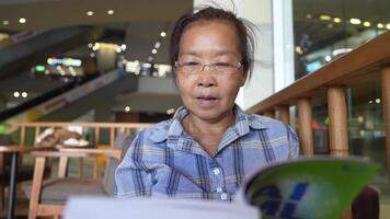 asiático mayor antiguo mujer es leyendo libro. video