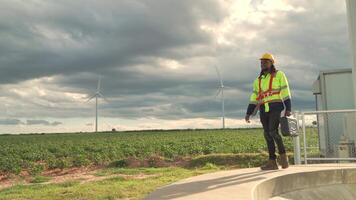 africano ingegnere Lavorando nel lavoro sul campo. lavoratore seduta e ispezionare costruzione e macchina in giro il progetto luogo. vento turbina elettrico di pulito risorsa energia e ambiente sostenibile. video