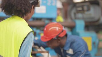 fabriek professioneel Afrikaanse en Aziatisch arbeider en manager inspecteur Aan machine en bespreken inspectie in de omgeving van fabriek. team ingenieurs repareren voor kwaliteit en inbedrijfstelling testen voordat operatie. video