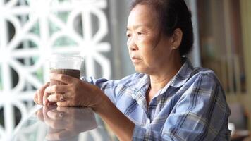 Asian senior old woman is drinking coffee and walking around outdoor pedestrian. video