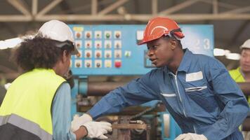 fabbrica professionale africano e asiatico lavoratore e manager ispettore su macchina e discutere ispezione in giro fabbrica. squadra ingegneri riparazione per qualità e la messa in produzione analisi prima operazione. video