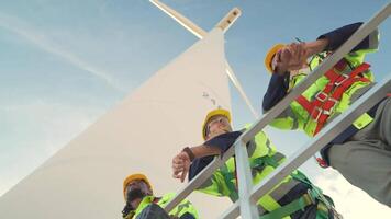 ingenieros trabajando en trabajo de campo al aire libre. trabajadores cheque y inspeccionar construcción y máquina alrededor el edificio proyecto sitio. viento turbinas para eléctrico limpiar energía y ambiente sostenibilidad. video