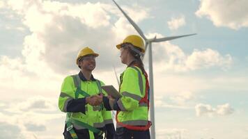 ingenieros trabajando en trabajo de campo exterior. trabajadores caminando y inspeccionar construcción y máquina alrededor proyecto sitio. viento turbina eléctrico de limpiar recurso energia y ambiente sostenible. video