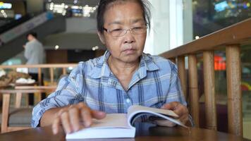 ásia Senior velho mulher é lendo livro. video