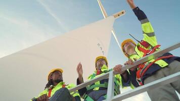 ingenieros trabajando en trabajo de campo al aire libre. trabajadores cheque y inspeccionar construcción y máquina alrededor el edificio proyecto sitio. viento turbinas para eléctrico limpiar energía y ambiente sostenibilidad. video