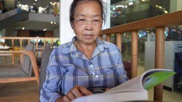 asiatico anziano vecchio donna è lettura libro. video
