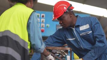 fábrica profesional africano y asiático trabajador y gerente inspector en máquina y discutir inspección alrededor fábrica. equipo ingenieros reparando para calidad y puesta en marcha pruebas antes de operación. video