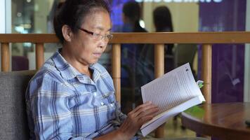 Aziatisch senior oud vrouw is lezing boek. video