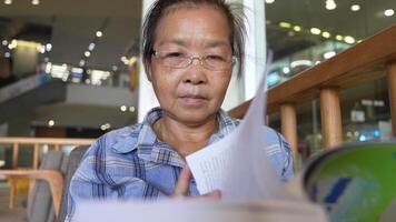 asiático mayor antiguo mujer es leyendo libro. video