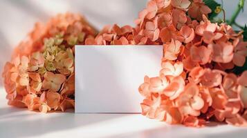 mockup of a white card beside orange hydrangea bouquet, soft pastel tones photo