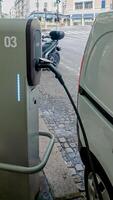 Electric vehicle charging at a public station on a city street, representing sustainable transportation and eco friendly travel concepts photo