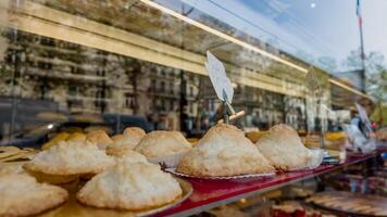 dorado marrón pasteles en monitor con precio etiqueta en un panadería escaparate, reflejando un urbano calle escena, relacionado a culinario letras y local gastronomía foto