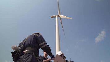 engenheiros homem e mulher inspecionando construção do vento turbina Fazenda. vento turbina com a energia armazenamento sistema operado de super energia corporação. trabalhadores encontro para Verifica por aí a área. video