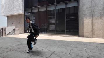 asiático hombre es bailando en cadera salto estilo a al aire libre espacio. profesional solo bailarín es ejecutando en público área. video