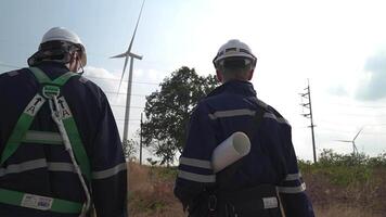 ingénieurs homme et femme inspecter construction de vent turbine cultiver. vent turbine avec un énergie espace de rangement système opéré par super énergie société. ouvriers réunion à vérifier autour le zone. video