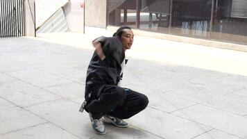 asiatisk man är dans i höft hopp stil på utomhus- Plats. professionell solo- dansare är utför i offentlig område. video