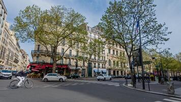 Springtime street scene in Paris, France, captured on April 14th, 2024, with fresh green trees and Parisian architecture, ideal for travel and seasonal themes photo