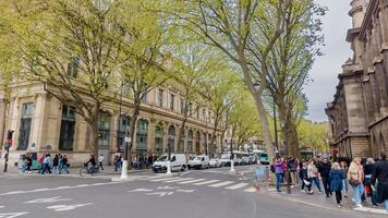 Diverse pedestrians crossing a tree lined Parisian street in springtime Paris, France, showcasing urban life and travel on April 14th, 2024 photo