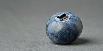 Macro shot of a blueberry with visible texture, isolated on a grey background photo