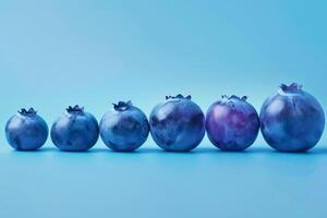 Stylized graphic of multiple blueberries in a descending size order, gradient blue background photo