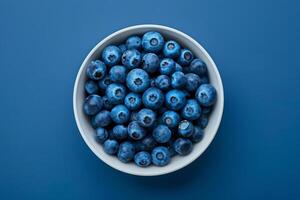 Top view of a many blueberry in a white bowl on a navy blue background photo