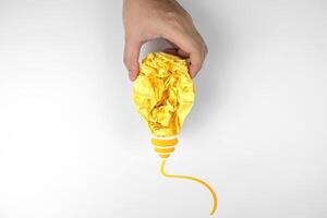 Creative ideas and Inspiration concepts. Human hand picks up crumpled colored paper in shape of yellow light bulb isolated on white background photo
