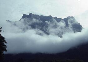 un avión volador terminado un montaña con nubes foto