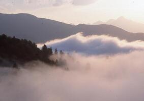 a plane flying over a mountain range with fog photo