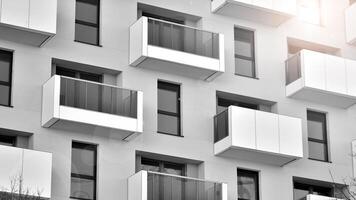 Fragment of the building's facade with windows and balconies. Modern apartment buildings on a sunny day. Facade of a modern residential building. Black and white. photo