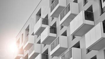 Fragment of the building's facade with windows and balconies. Modern apartment buildings on a sunny day. Facade of a modern residential building. Black and white. photo