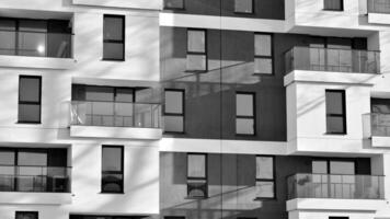 Fragment of the building's facade with windows and balconies. Modern apartment buildings on a sunny day. Facade of a modern residential building. Black and white. photo