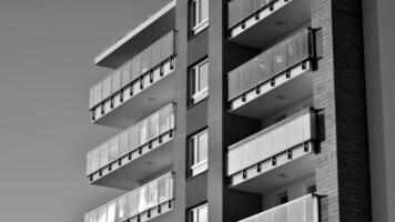 Fragment of the building's facade with windows and balconies. Modern apartment buildings on a sunny day. Facade of a modern residential building. Black and white. photo