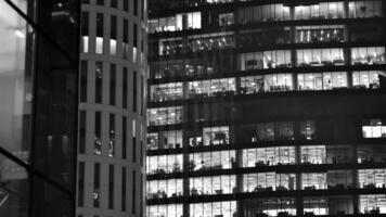 Pattern of office buildings windows illuminated at night. Glass architecture ,corporate building at night - business concept. Black and white. photo