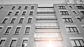 Fragment of the building's facade with windows and balconies. Modern apartment buildings on a sunny day. Facade of a modern residential building. Black and white. photo