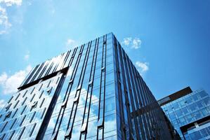 Glass building with transparent facade of the building and blue sky. Structural glass wall reflecting blue sky. Abstract modern architecture fragment. Contemporary architectural background. photo