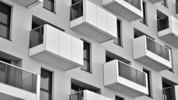 Fragment of the building's facade with windows and balconies. Modern apartment buildings on a sunny day. Facade of a modern residential building. Black and white. photo