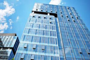 Glass building with transparent facade of the building and blue sky. Structural glass wall reflecting blue sky. Abstract modern architecture fragment. Contemporary architectural background. photo