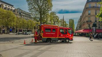 French firefighter in uniform by a red fire engine marked Sapeurs Pompiers de Paris on an emergency call in Paris, France, on April 14th, 2024 photo