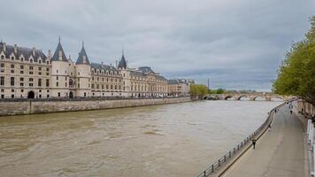 Cloudy day view of the historic Conciergerie along the Seine River in Paris, France, ideal for travel, architecture themes, and Bastille Day celebrations photo
