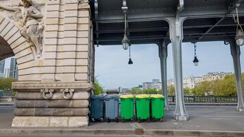 vistoso reciclaje contenedores forrado arriba debajo un puente en un urbano configuración, representando residuos administración y ambiental conservación conceptos foto